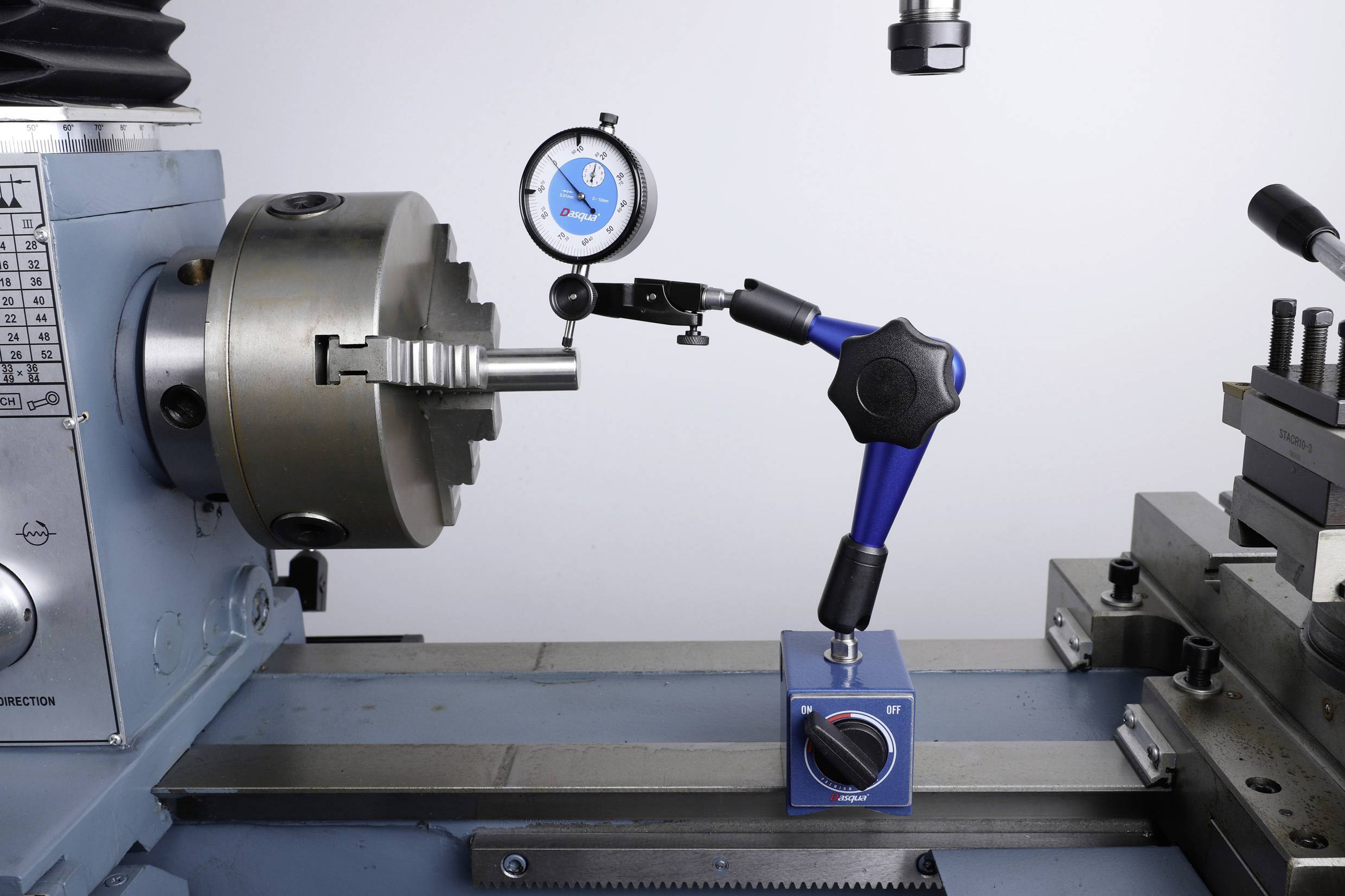 Établi de machine avec un tour. Un comparateur monté sur un support magnétique mesure la précision d'une pièce dans le mandrin.