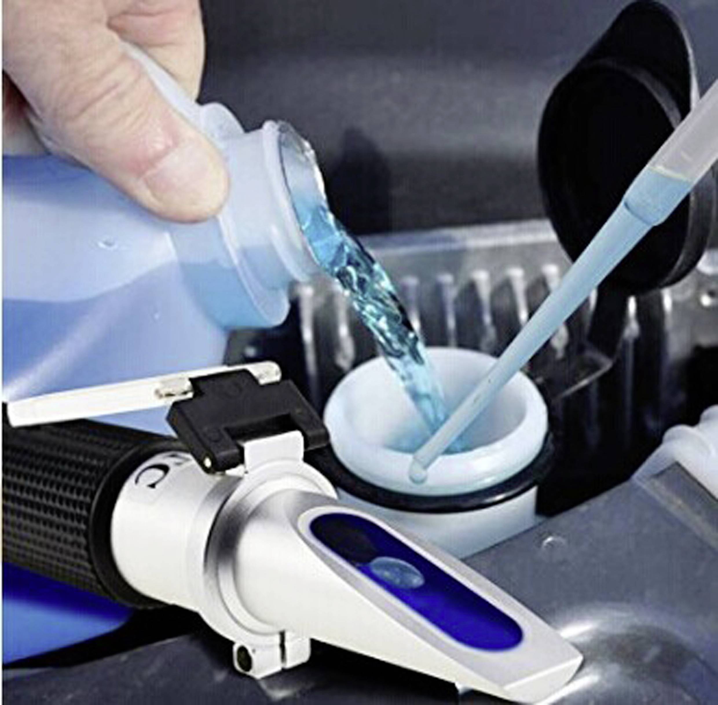 Une personne verse un liquide bleu dans un récipient à côté d'un réfractomètre. Cet instrument mesure la densité ou la concentration des liquides.