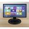 Un écran d'ordinateur affiche une surface en mosaïque avec des icônes d'applications et de widgets sur une table en bois.