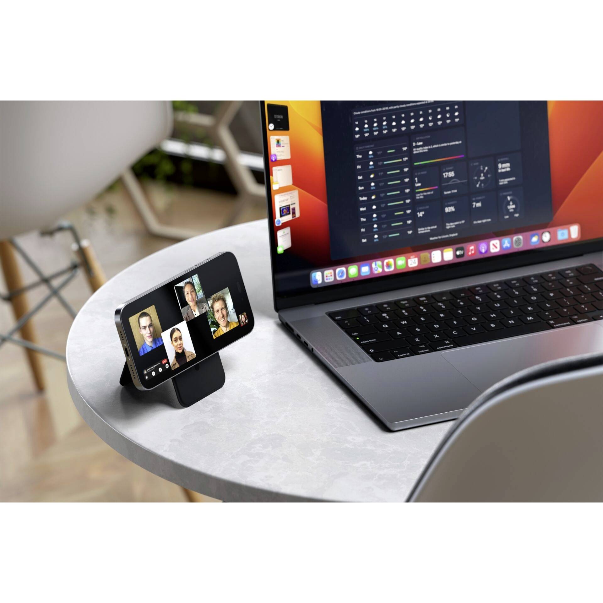 Un ordinateur portable affiche du code de programmation ; à côté, un téléphone portable sur un support montre un appel de visioconférence avec quatre personnes visibles.