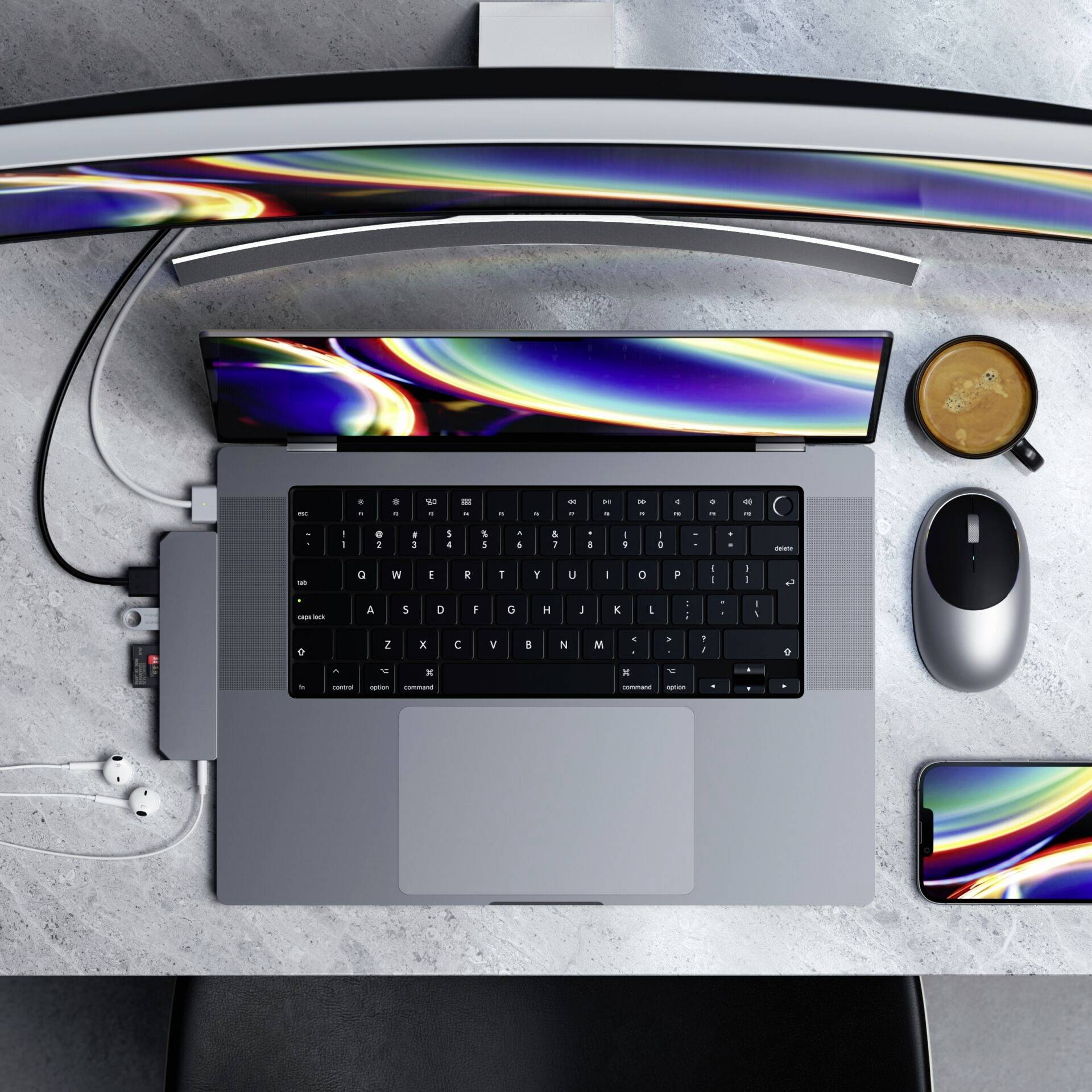 Un ordinateur portable sur un bureau, entouré d'un écran, d'une souris, d'un smartphone, d'une tasse de café et de câbles.