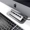 Un hub USB-C argenté à quatre ports est branché à un ordinateur, à côté d'un clavier noir et d'un ordinateur portable.