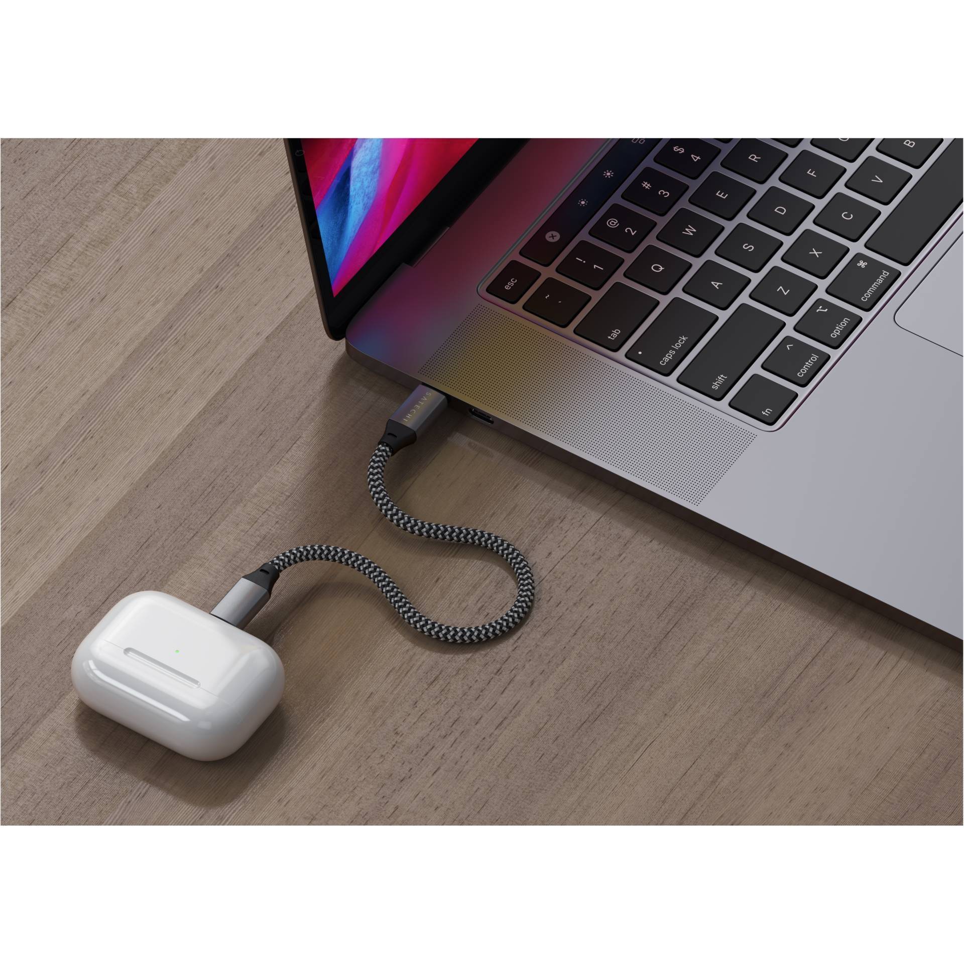 Le câble de chargement des AirPods est connecté à un ordinateur portable et repose sur une table en bois. L'écran de l'ordinateur portable affiche un écran lumineux.