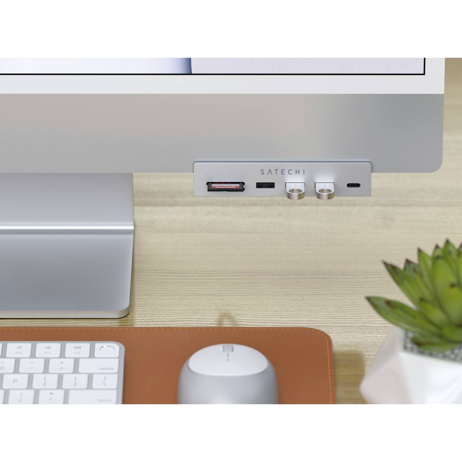 Un écran d'ordinateur avec un hub USB Satechi sur un bureau. À côté se trouvent un clavier et une souris.
