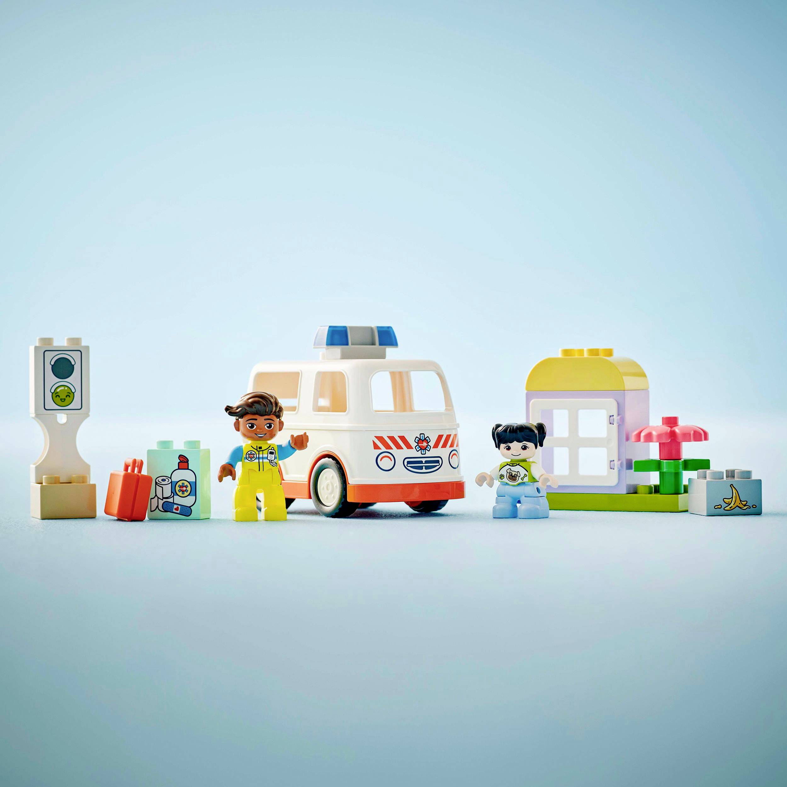 Deux figurines avec une ambulance et un hôpital construits à partir de blocs de construction colorés. Un médecin avec un stéthoscope, un enfant, une ambulance et un feu de signalisation.
