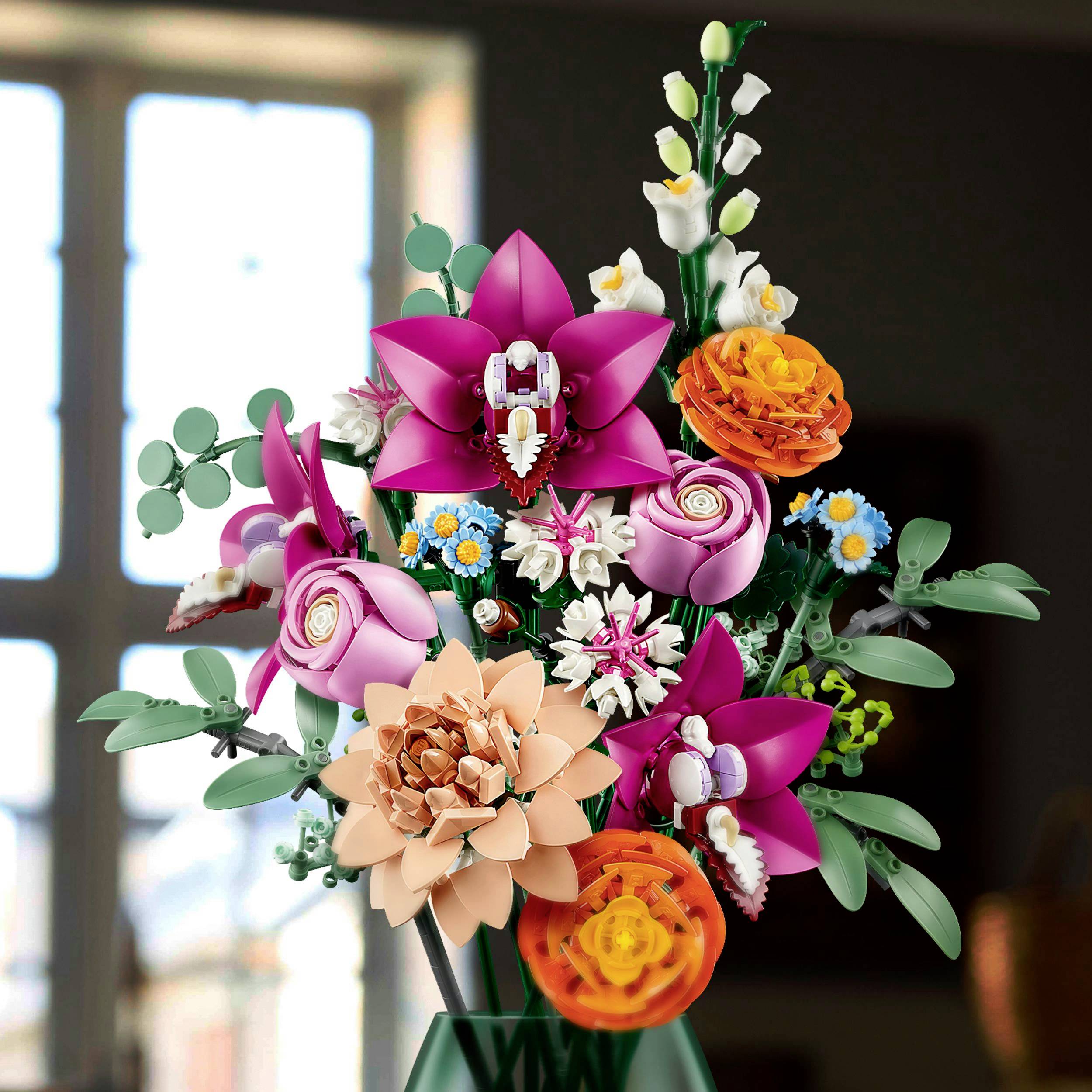 Un bouquet coloré de lys roses, de roses jaunes et de feuilles vertes dans un vase devant une fenêtre à la lumière du jour.