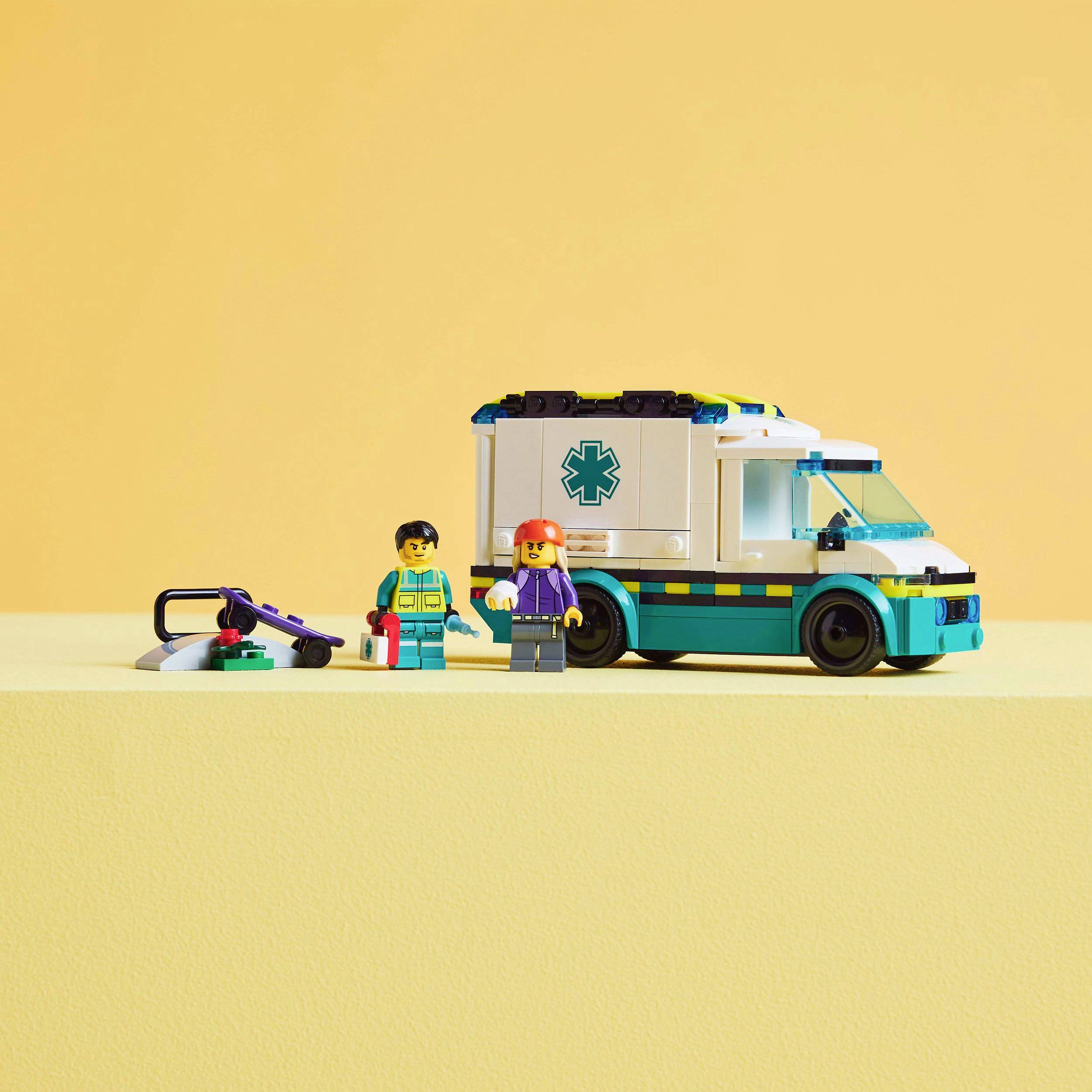 Deux figurines en blocs de construction sont posées à côté d'une ambulance jouet sur une table couleur crème. Une scie est posée à proximité.