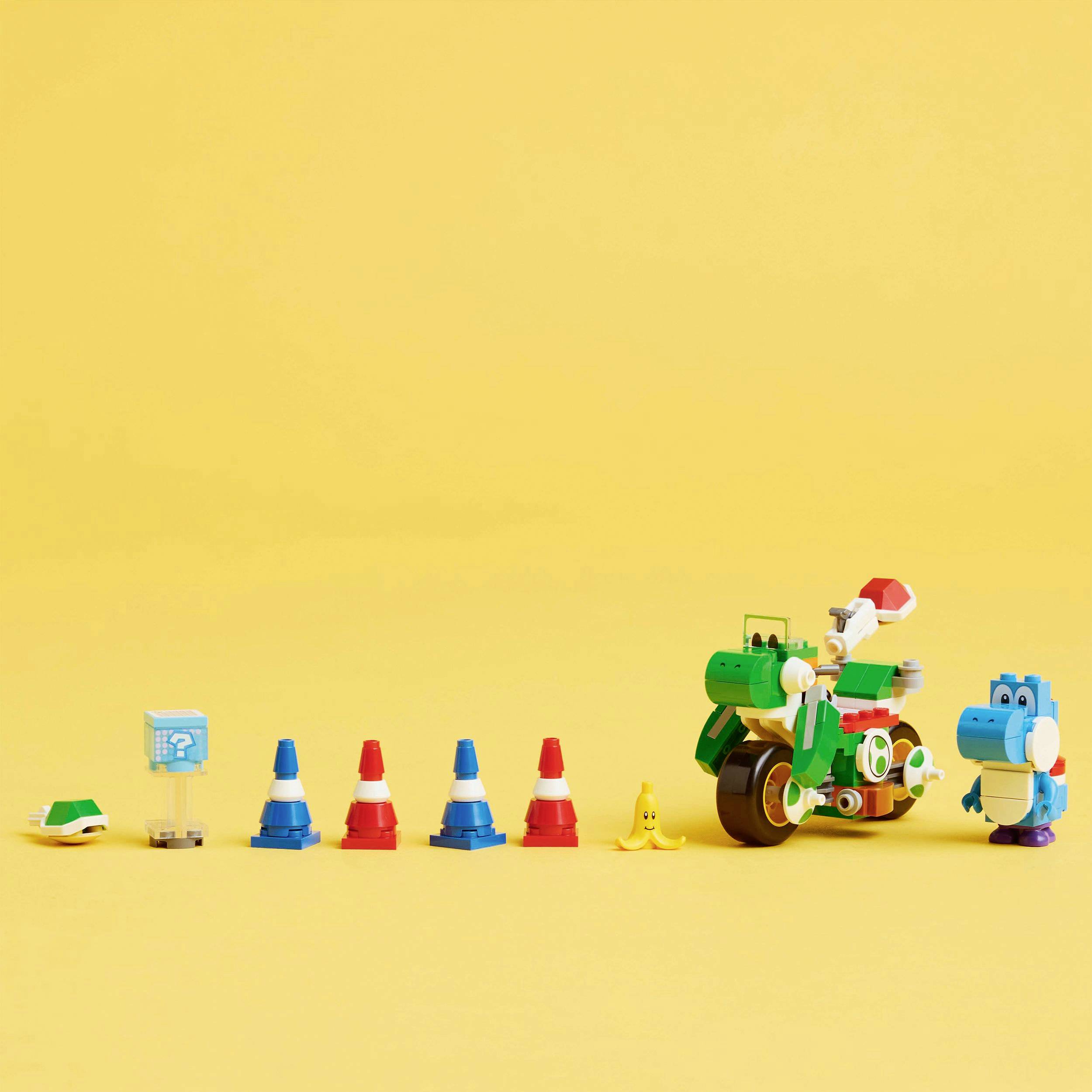Petites figurines sur un fond jaune, comprenant une moto verte, des cônes colorés, une tortue et un dinosaure.