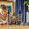 Un enfant joue avec un ensemble LEGO représentant une maison hantée. L'ensemble présente des figurines et des détails effrayants sur une table en bois.