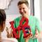 Une personne tient devant une autre un objet rouge en forme du mot 'LOVE', toutes deux se sourient mutuellement.