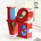 Des blocs Lego rouges forment le mot 'LOVE'. Environnement lumineux et moderne.