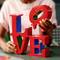 Une personne tient un modèle LEGO coloré du mot 'LOVE', montrant une construction créative avec des briques rouges et bleues.