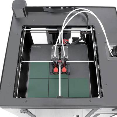 Imprimante 3D en action, créant un objet sur sa plateforme. Les buses d'impression se déplacent avec précision au-dessus d'une surface carrée.
