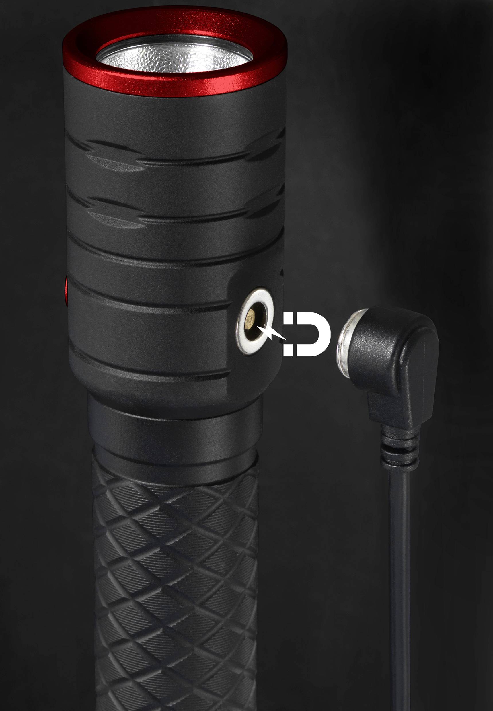 Une lampe de poche noire avec un bord rouge montre un port de charge magnétique latéral auquel un câble de charge est connecté.