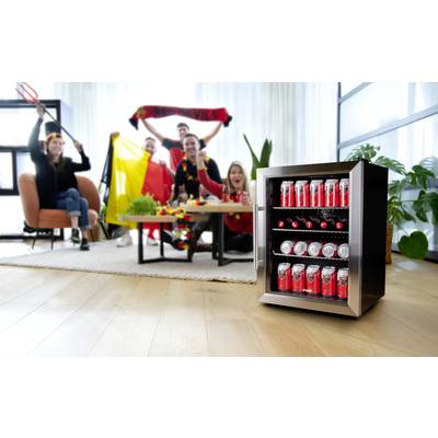 Un groupe applaudit devant une table avec un drapeau belge, tandis qu'un petit réfrigérateur avec des canettes de boisson se trouve au premier plan.