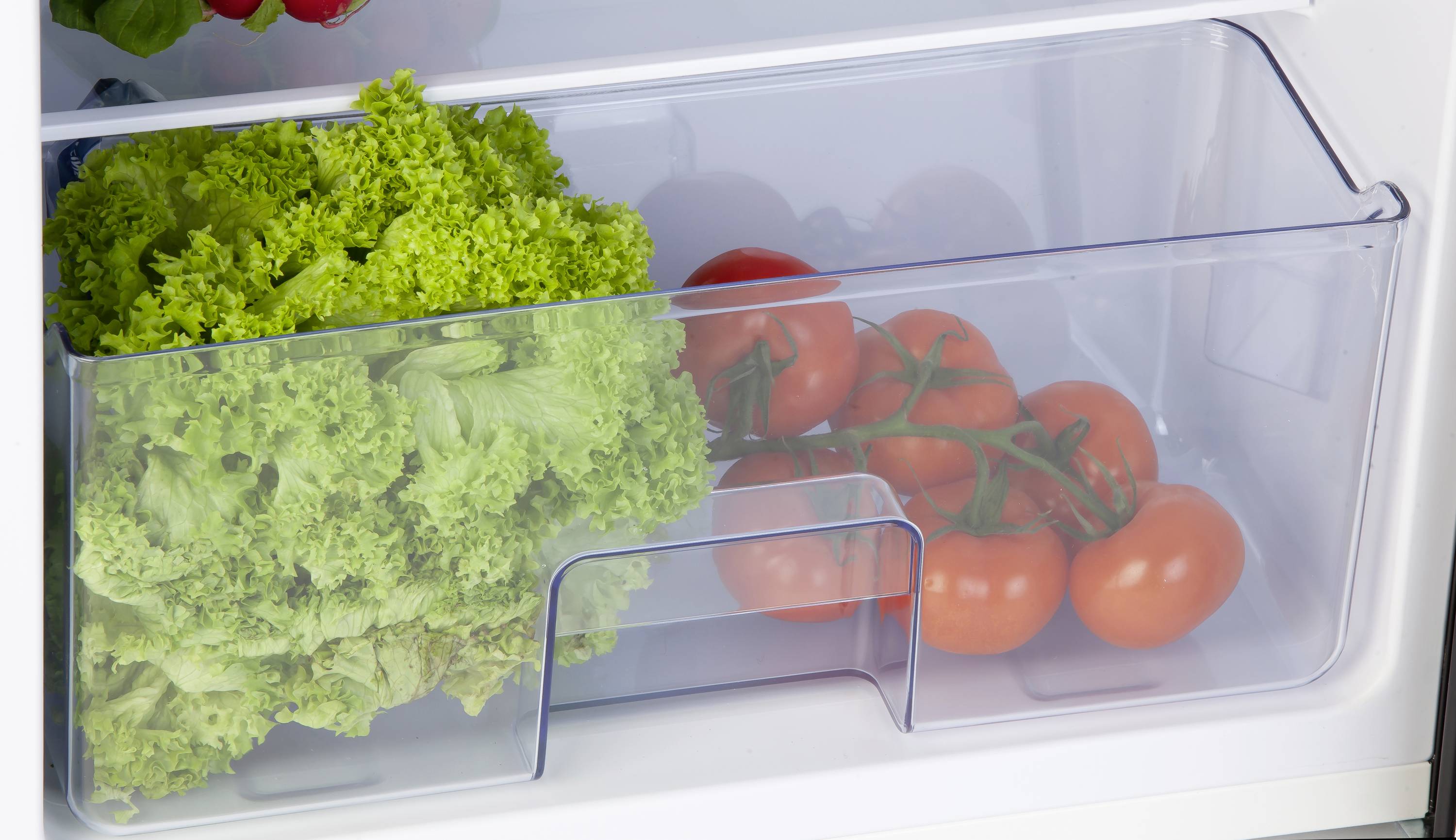 Un tiroir du réfrigérateur contient de la salade fraîche et des tomates.