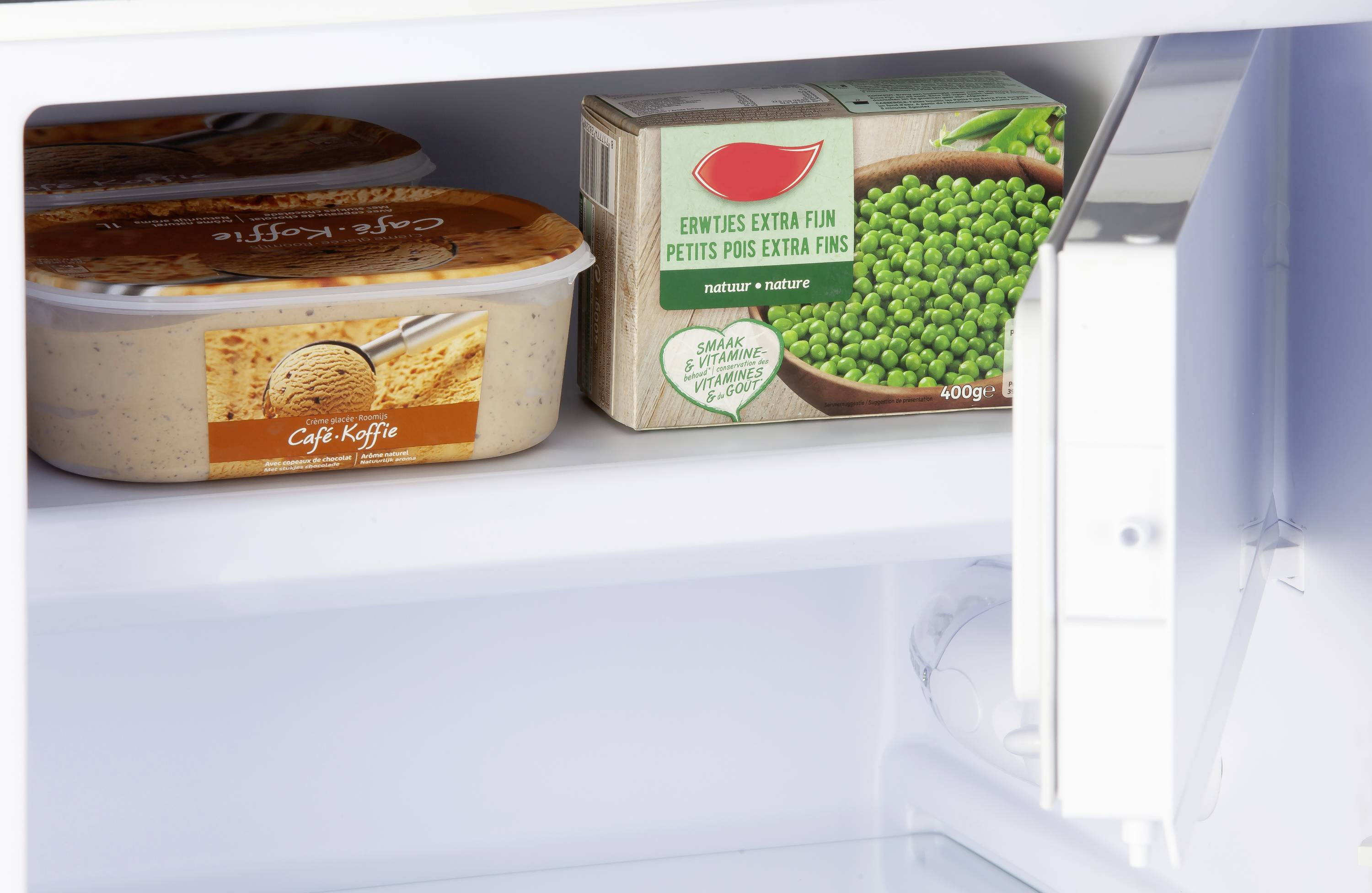 Congélateur contenant un paquet de petits pois et deux contenants de crème glacée. Le paquet de petits pois arbore un logo représentant un oiseau rouge.
