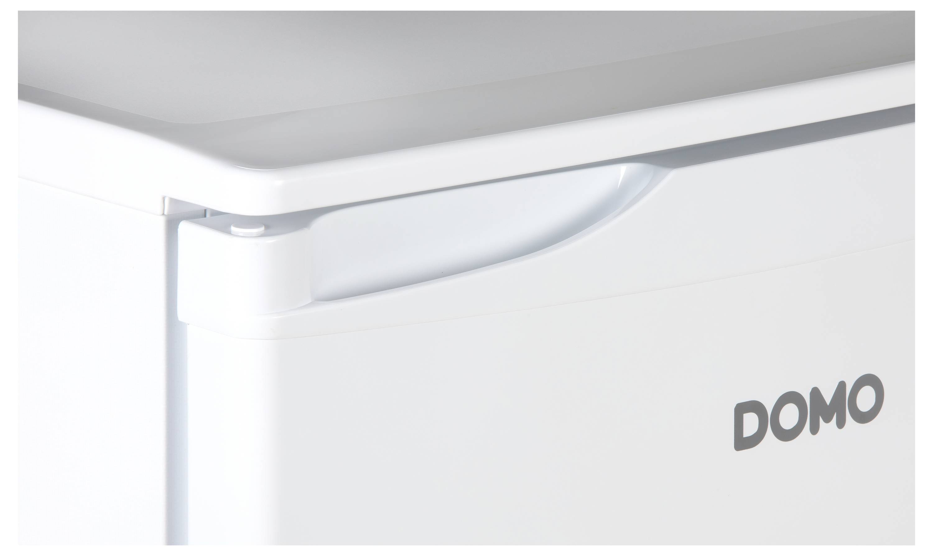 Partie supérieure d'un petit réfrigérateur blanc aux coins arrondis, avec le logo 'DOMO' sur la droite.