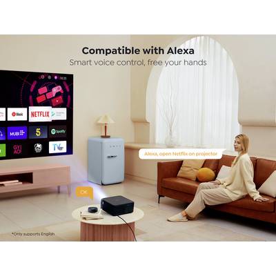 Une femme assise sur un canapé commande un projecteur par commande vocale via Alexa, qui affiche des services de streaming sur un écran.