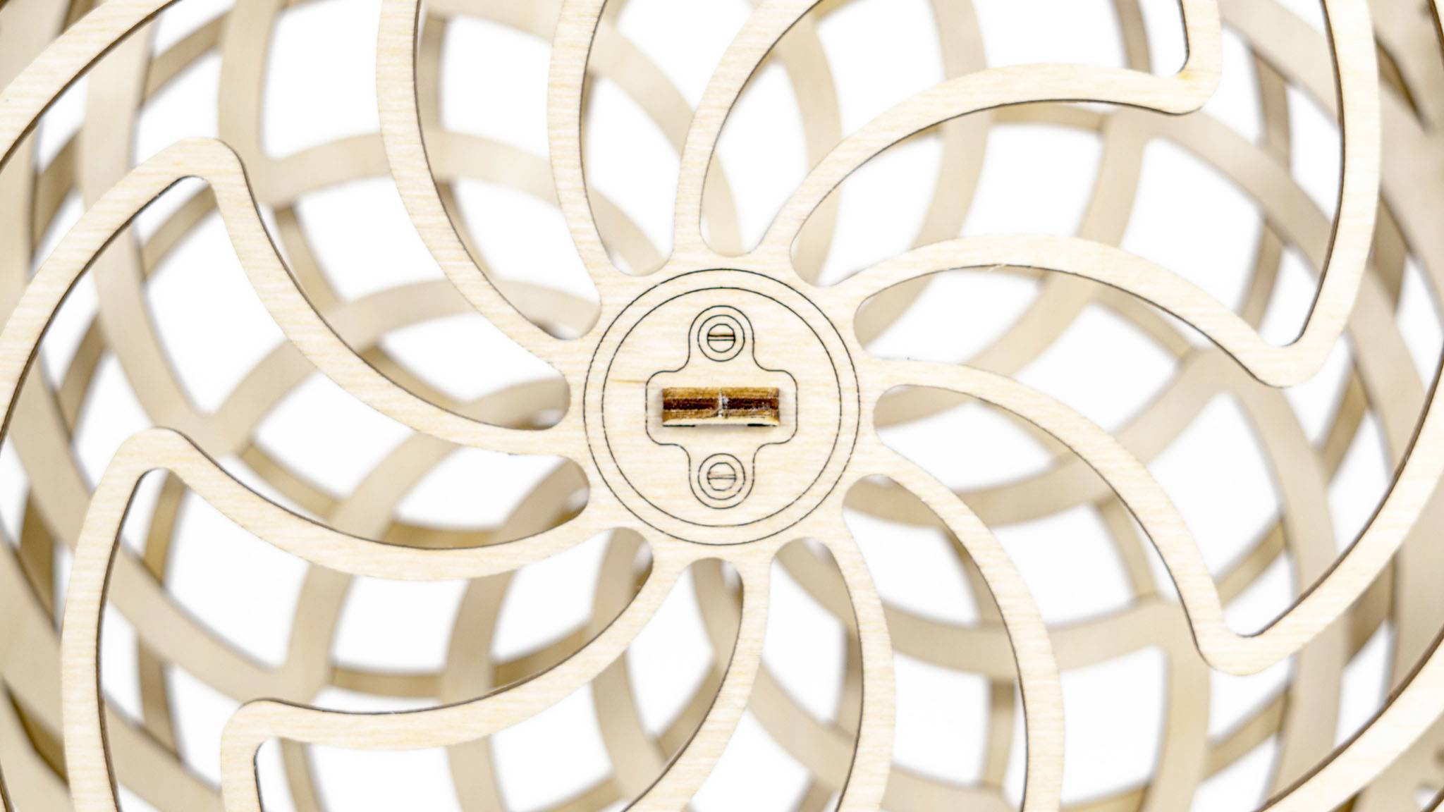 Œuvre d'art en bois avec un motif en spirale et un détail central en forme de croix évoquant une escargot ou une fleur.