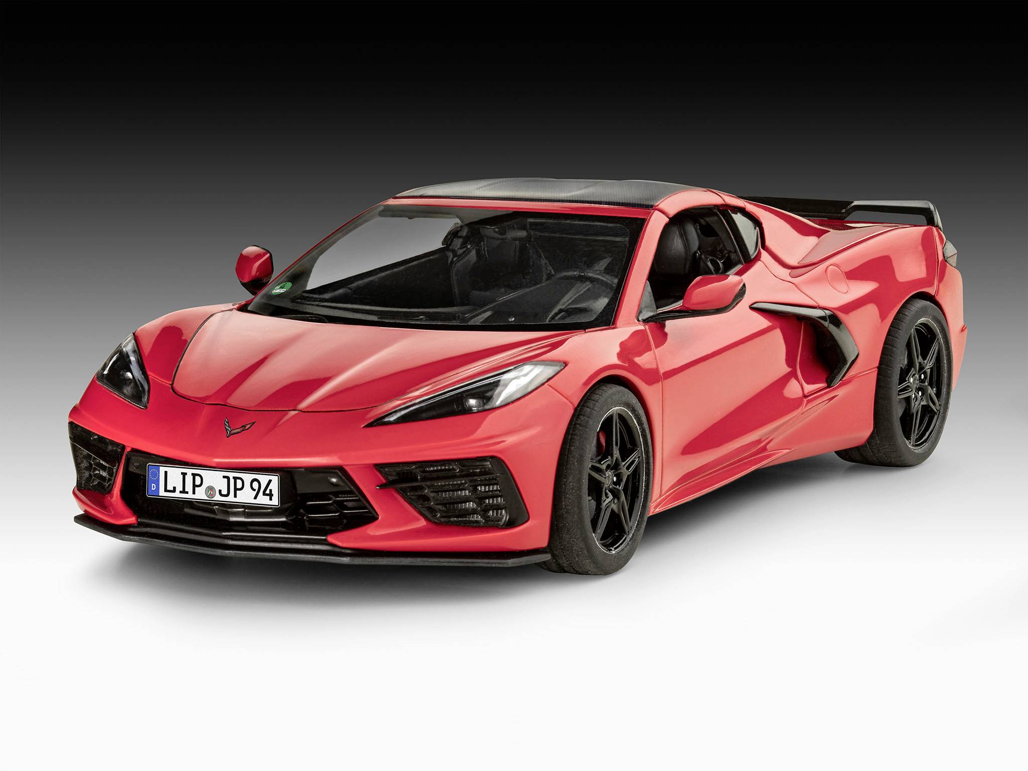 Une voiture de sport rouge est garée sur un sol clair devant un arrière-plan sombre. Elle présente un design moderne et des jantes noires.