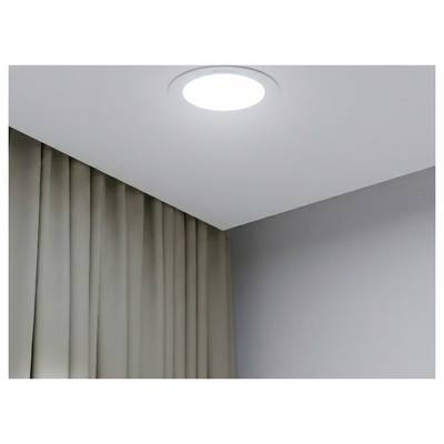 Lumière ronde montée au plafond au-dessus de rideaux beige fermés et d'un coin de mur gris uni dans une pièce.