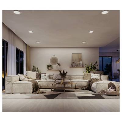 Salon moderne avec un canapé sectionnel beige, une table basse, des plantes, des œuvres d'art murales et des luminaires encastrés au plafond au crépuscule.