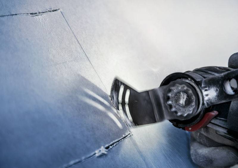 Un outil oscillant coupe précisément à travers une surface métallique. Des étincelles volent tandis que la lame tranche le matériau.