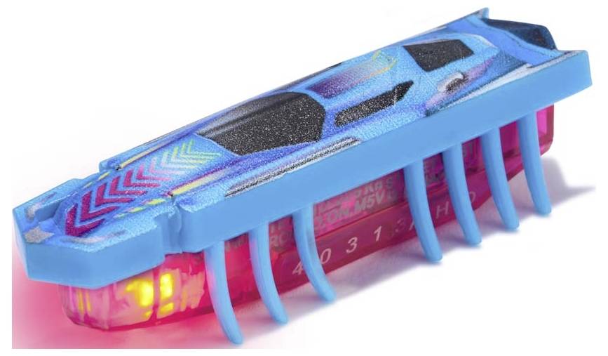 Un petit jouet lumineux en forme de voiture de course avec des pattes, ressemblant à un insecte robotique, sur une surface blanche.