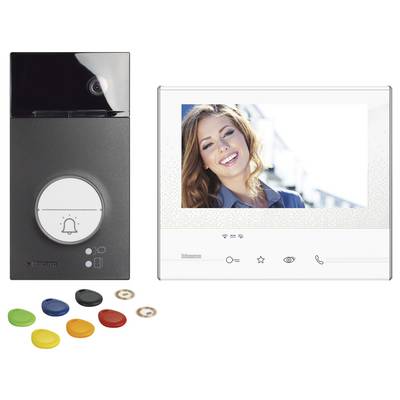 Sonnette vidéo avec moniteur. À gauche : Sonnette avec caméra et touches de couleur interchangeables. À droite : Le moniteur affiche l'image d'une personne souriante.