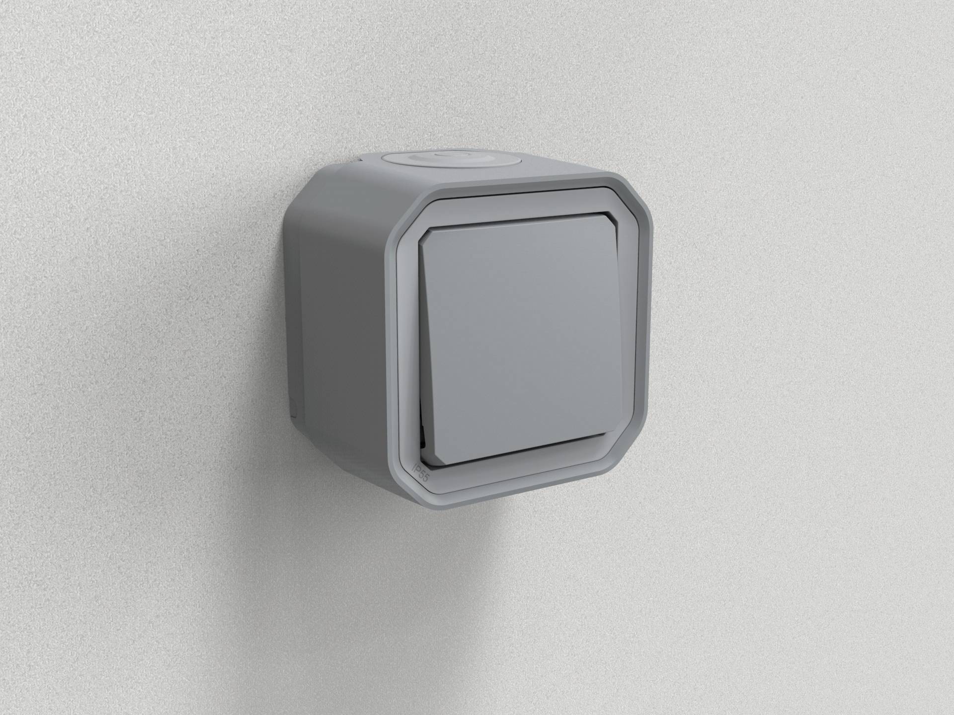 Une prise électrique grise, carrée, avec couvercle, fixée à un mur, typique des espaces extérieurs.