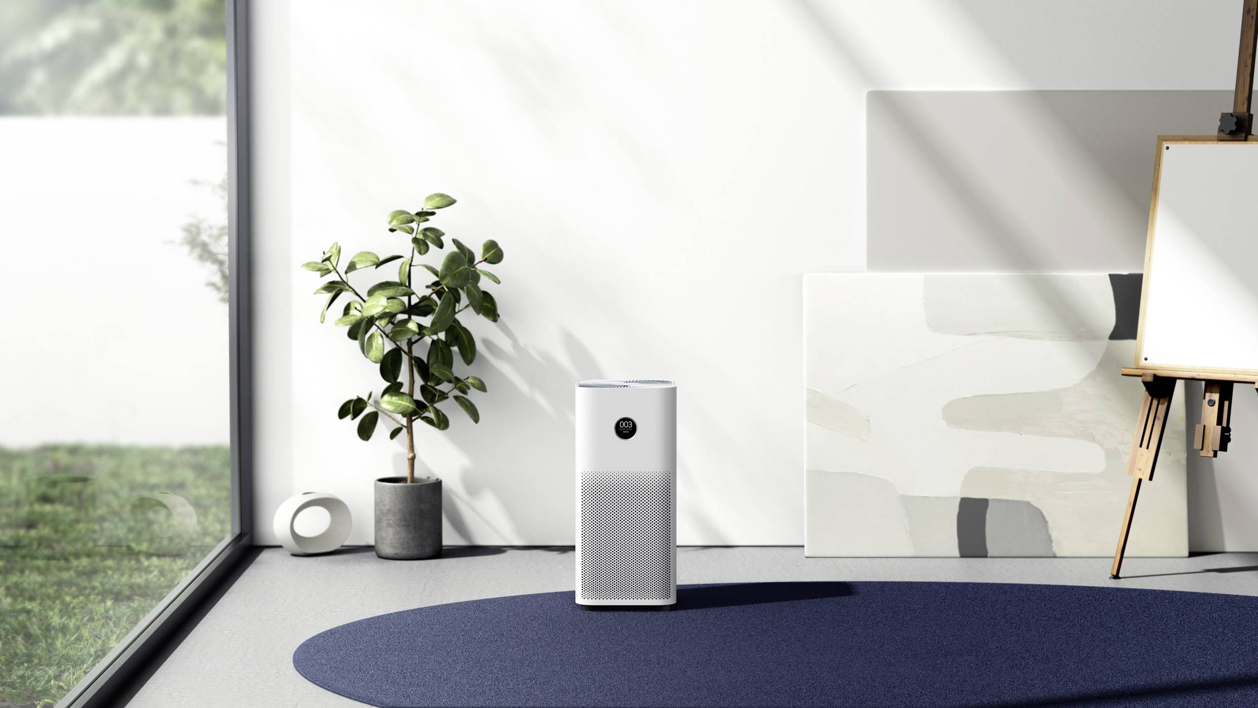 Un purificateur d'air moderne est placé dans une pièce lumineuse à côté d'une plante et d'un chevalet avec une toile, éclairé par la lumière du jour.