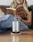 Une personne est assise sur un canapé et lit un livre. Au premier plan, une tasse isotherme argentée est posée sur une table.