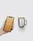 Une main tient un smartphone affichant une température de 57 degrés. À côté se trouve un gobelet argenté contenant une boisson chaude.