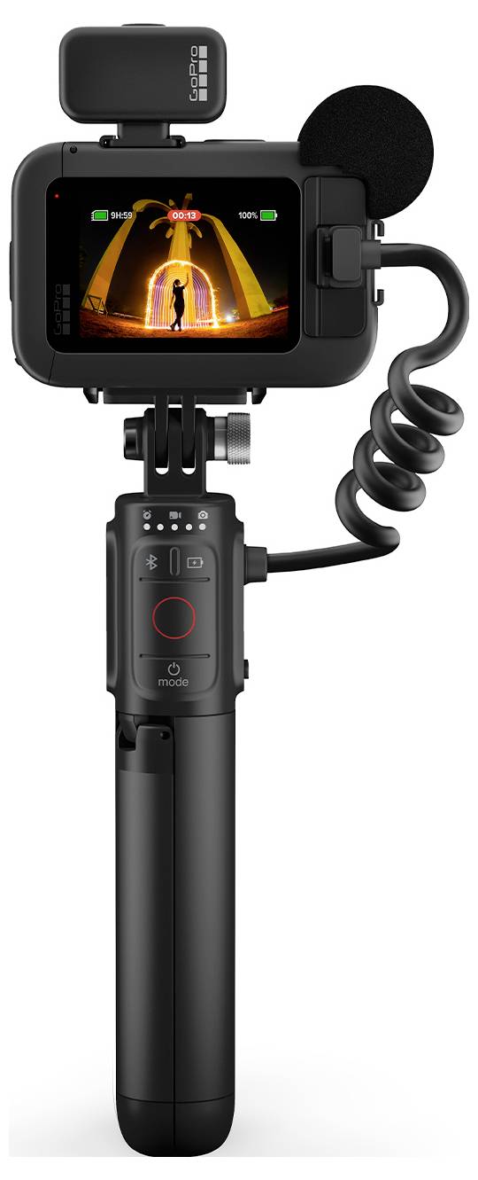 Appareil photo numérique avec microphone et trépied, l'écran affiche une personne devant un portail éclairé.