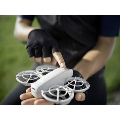 Une personne tient un petit drone équipé de grilles de protection circulaires, prêt au décollage. Une main pointe vers le dessus du drone.