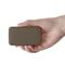 Une main tient une batterie externe brune rectangulaire à surface texturée.