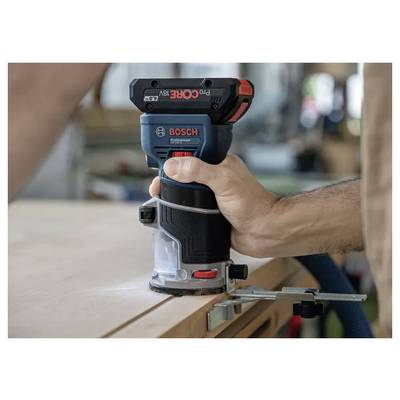 Une personne utilise une défonceuse sans fil Bosch sur une surface en bois, en se concentrant sur un travail du bois précis avec un guide de coupe maintenu par une pince.