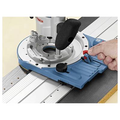 Un main ajustant un levier rouge sur une base de défonceuse bleue fixée à une rail métallique, indiquant une configuration pour des tâches de menuiserie ou de défonçage précises.
