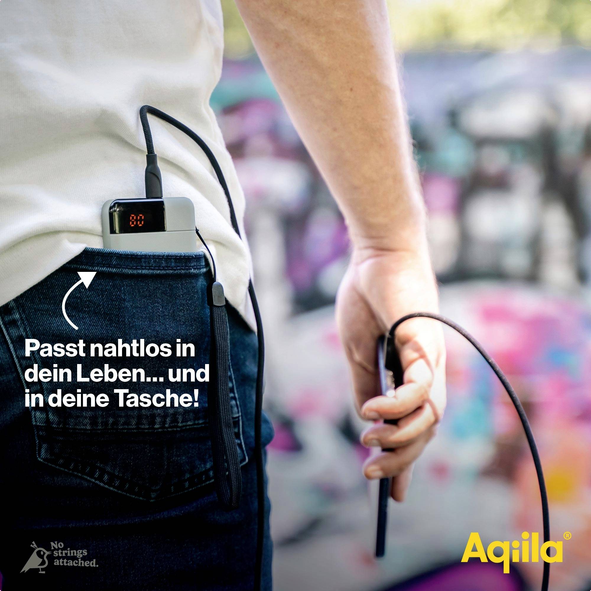 Une personne range une batterie externe portable dans la poche de son pantalon. Texte : 'S'intègre parfaitement à votre vie... et à votre poche !'