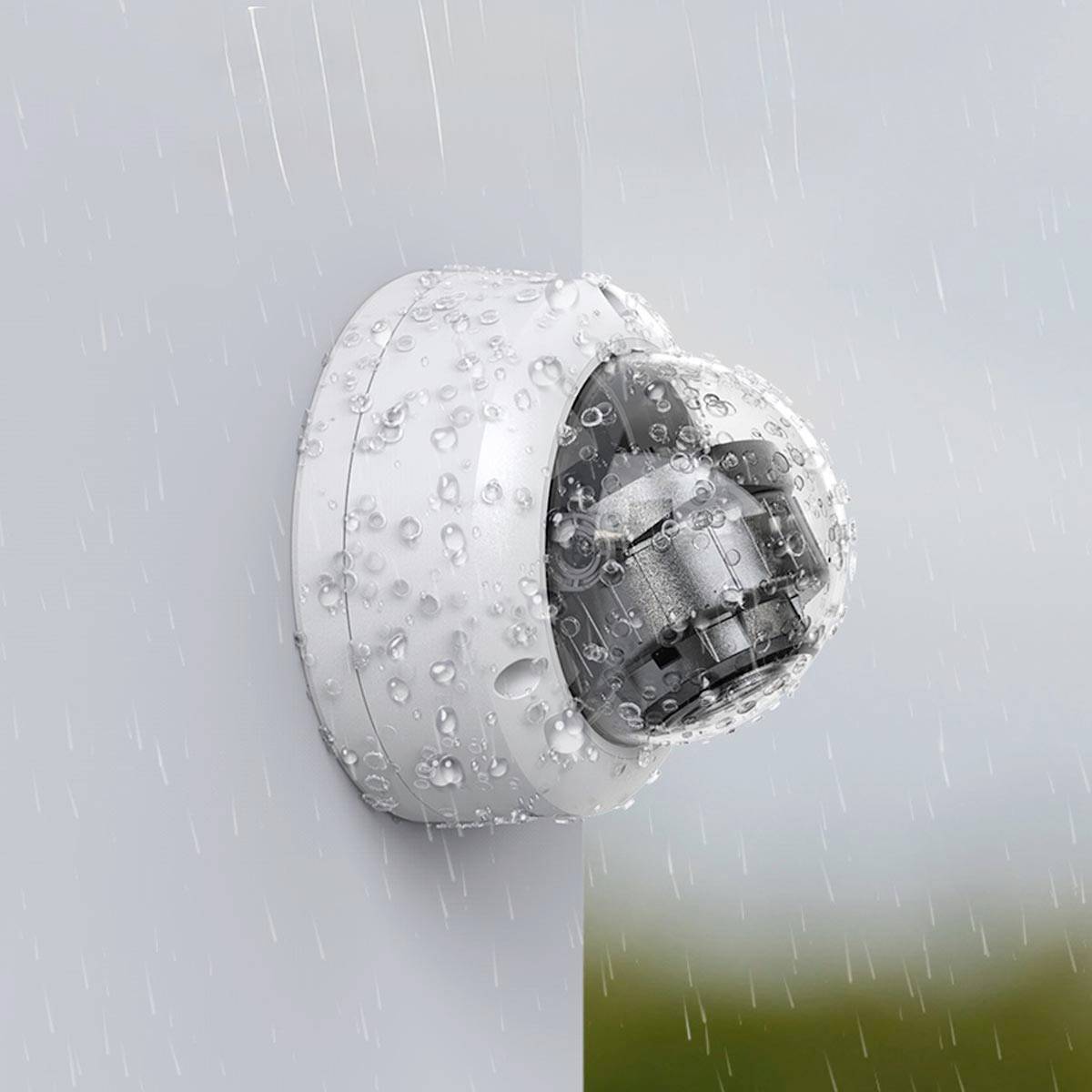 Une caméra de surveillance blanche, résistante à la pluie, est montée sur un mur et recouverte de gouttes de pluie. Elle démontre sa résistance par temps inclement.
