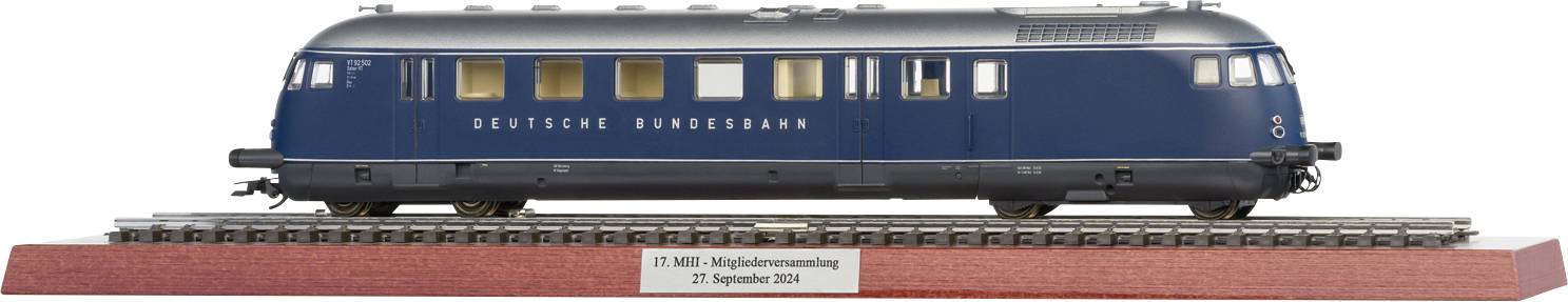 Modèle d'un train bleu sur des rails, présenté sur un socle en bois portant l'inscription 'Deutsche Bundesbahn' et une indication de date.