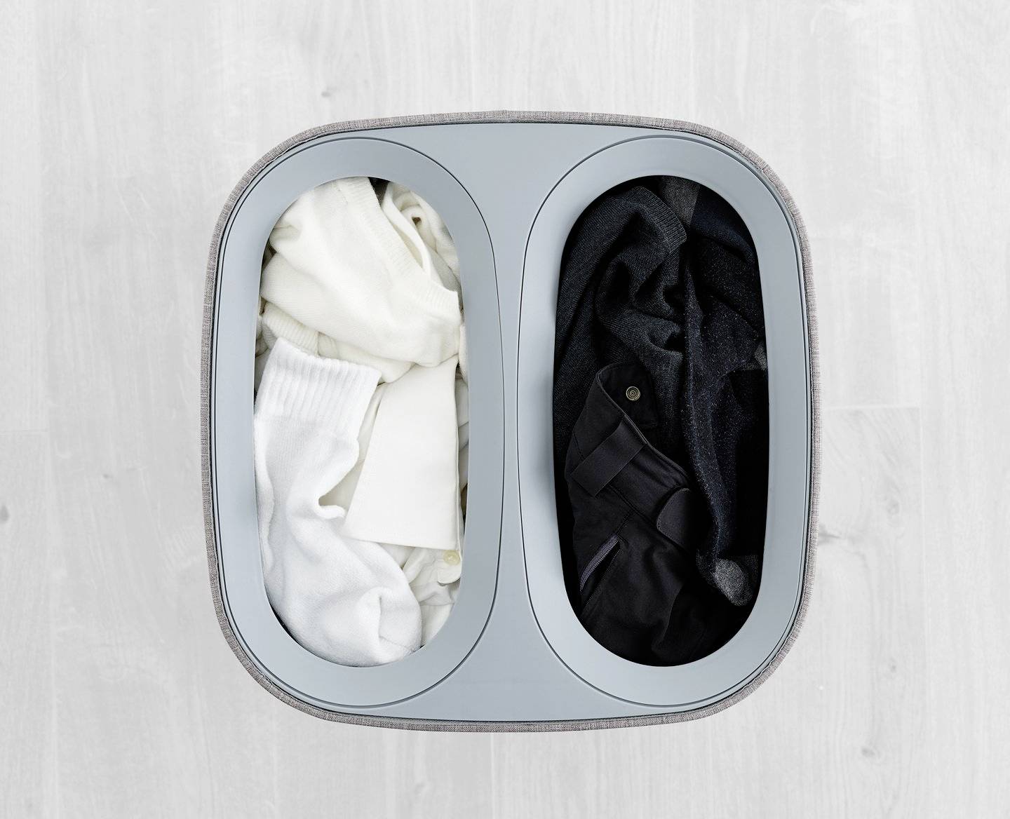 Un panier à linge à deux compartiments : à gauche les vêtements blancs, à droite les vêtements foncés.
