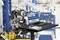 Un ordinateur portable est posé sur une table dans une usine. L'écran affiche un logiciel de fabrication. À l'arrière-plan, on peut voir des machines et des lignes de production.