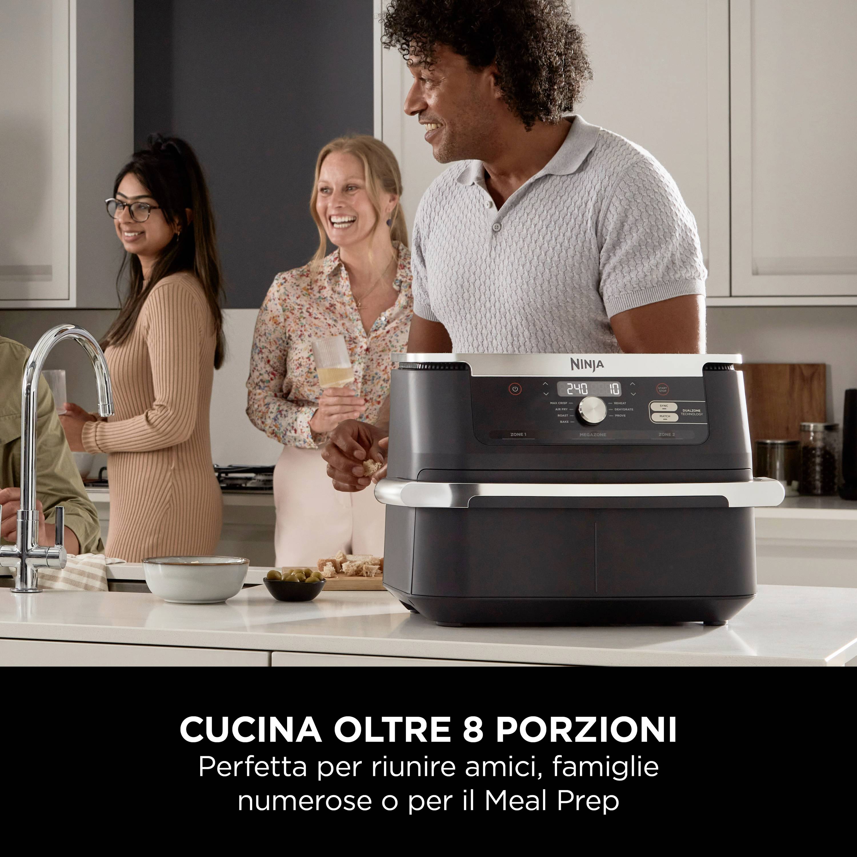 Un groupe de quatre personnes sourit et discute dans une cuisine moderne. Devant eux se trouve un grand four de cuisine.