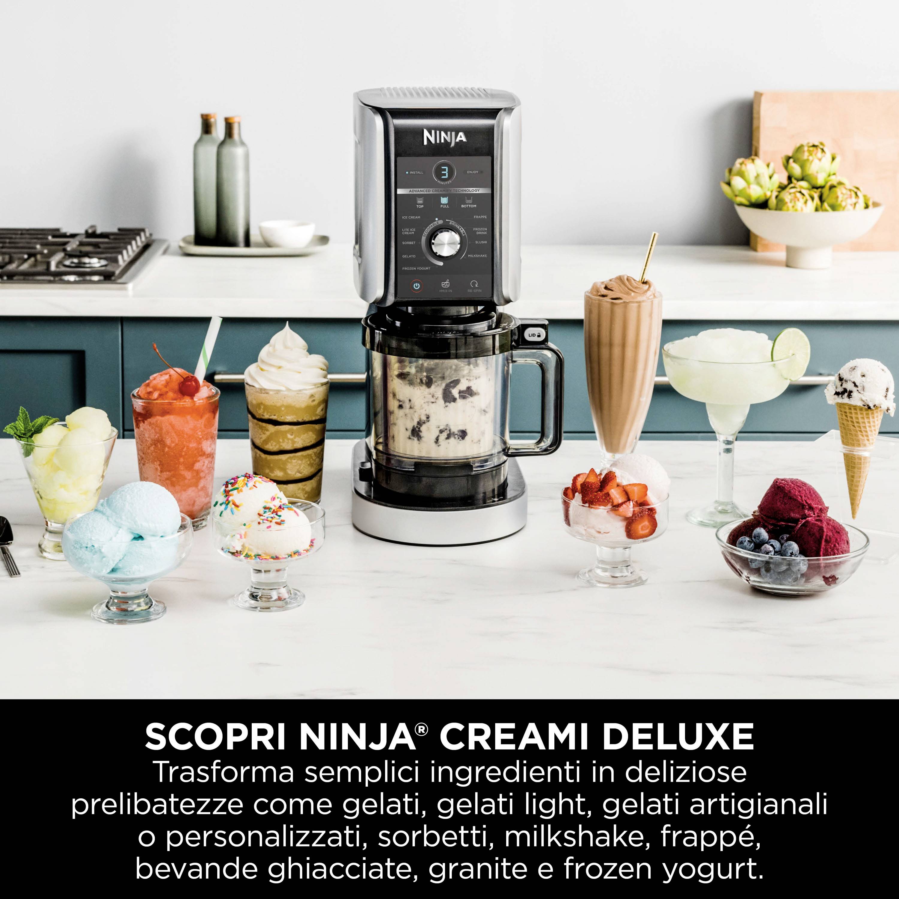 Machine Ninja Creami sur un comptoir de cuisine avec différentes sortes de glaces, milkshakes et garnitures. Ustensiles de cuisine et fleurs en arrière-plan.