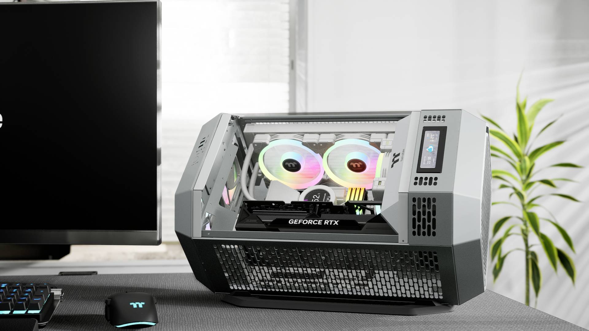 Ordinateur de gaming externe avec carte graphique GeForce RTX visible et éclairage RVB, posé à côté d'un écran sur un bureau.