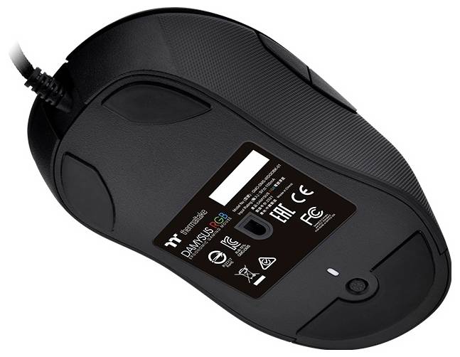 Une souris de jeu noire vue de dessous, montrant le logo du fabricant, le nom du modèle « DAMYSUS RGB » et les symboles de conformité réglementaire.