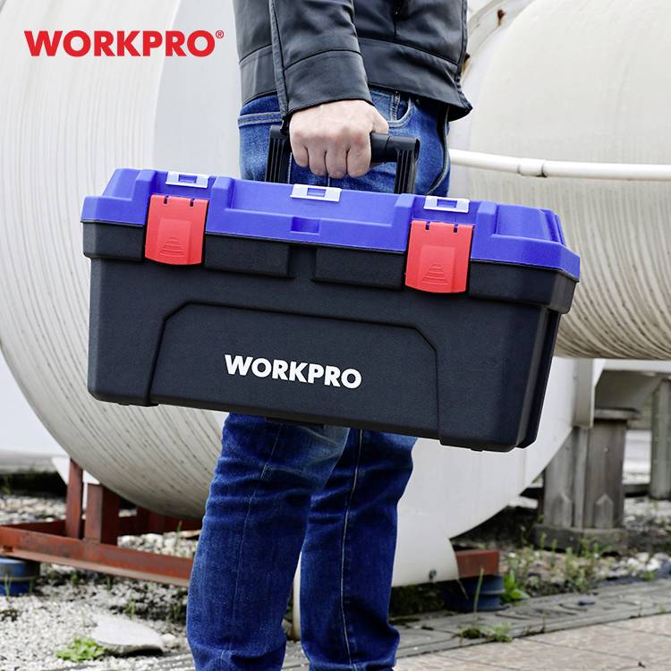 Une personne tient une boîte à outils noire avec des accents bleus et rouges. En arrière-plan, un décor industriel. La marque 'WORKPRO' est visible.