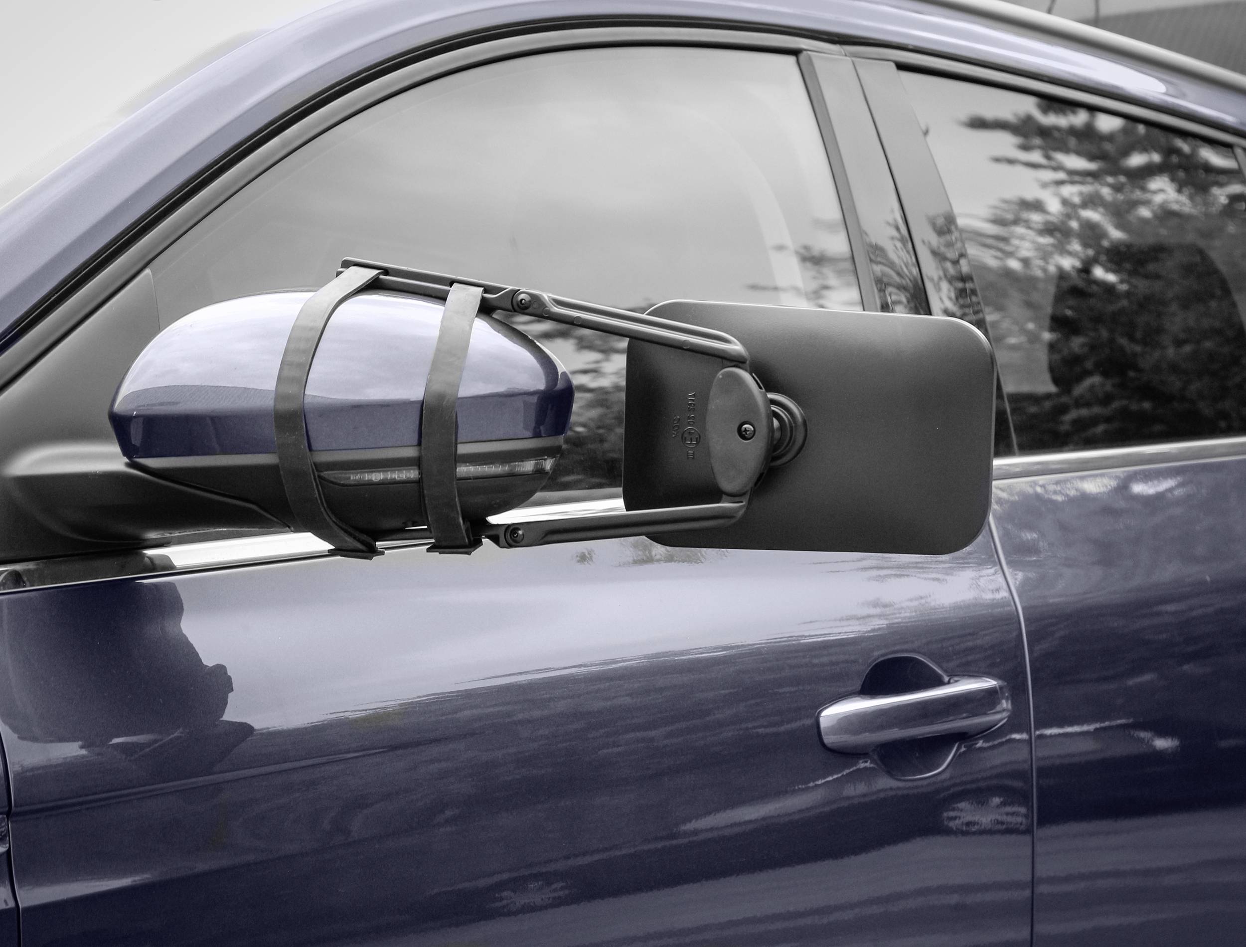 Une voiture bleue avec un rétroviseur supplémentaire pour remorque côté conducteur, fixé par des sangles au-dessus du rétroviseur latéral standard.